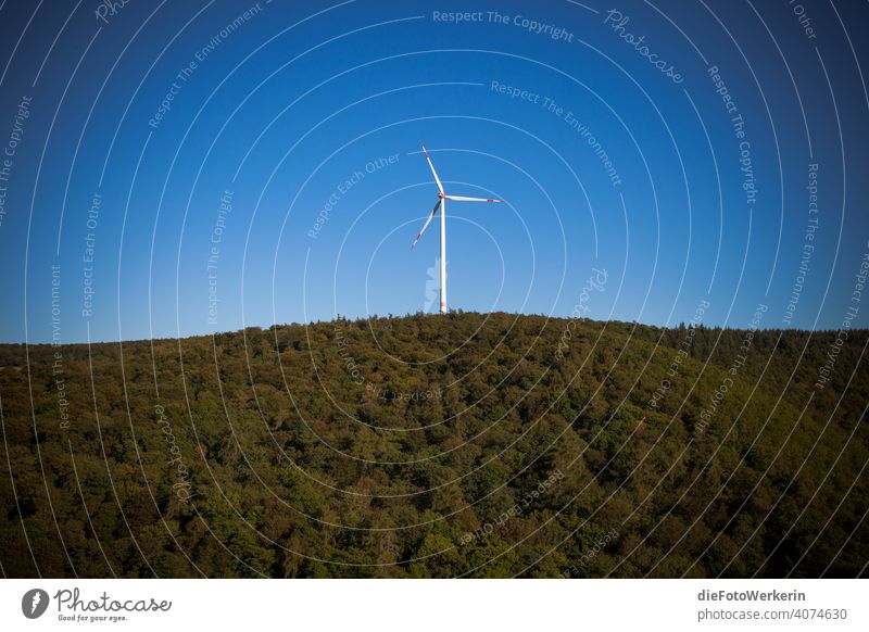 Wind turbine in front of blue sky above forested mountains Tree Germany Europe vulture layer Wood Hunsrück Landscape Nature technology Forest West Germany
