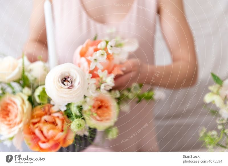 Woman hands touching a bouquet of flowers. table woman young caucasian hold holding dress white vase candles soft light decoration close up background interior