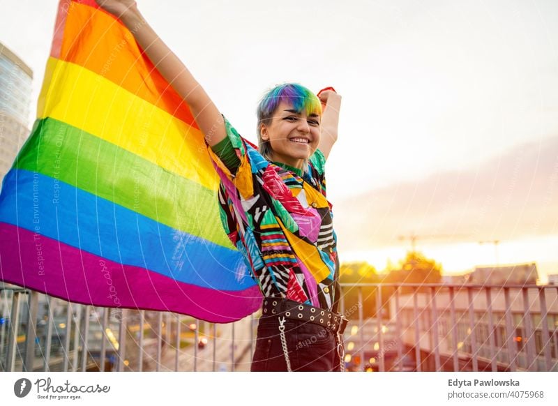 Portrait of happy non-binary person waving rainbow flag gender fluid gender fluidity lgbt equality homosexual lesbian pride gay parade man make-up identity
