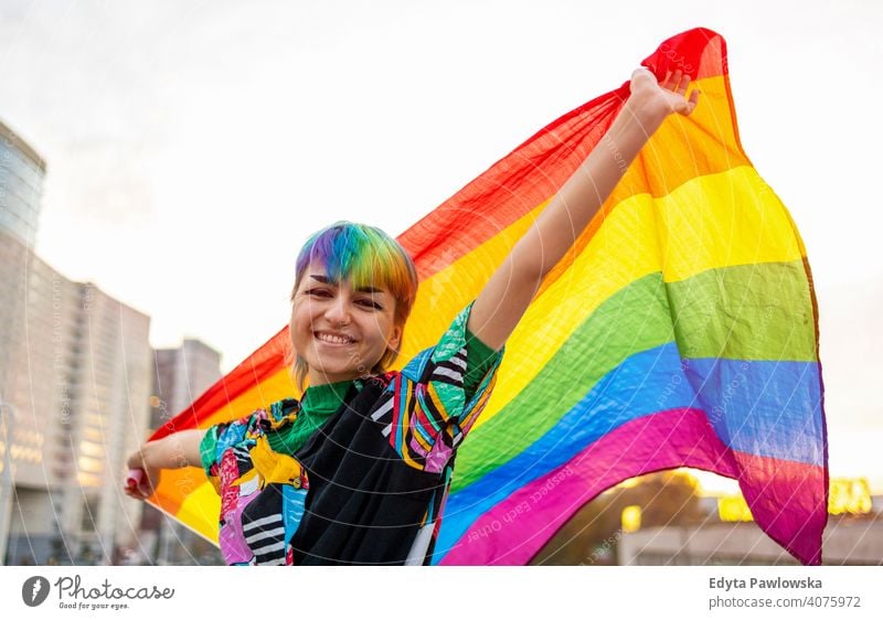 Portrait of happy non-binary person waving rainbow flag gender fluid gender fluidity lgbt equality homosexual lesbian pride gay parade man make-up identity