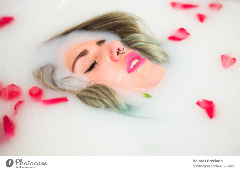 Young woman taking a relaxing bath of milk and roses young wet wellness wellbeing water tub treatment spa relaxation pleasure female hydrotherapy hot healthy