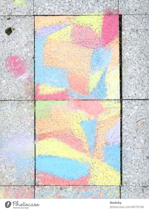 Grey paving stones painted with coloured chalk by a child on a balcony in Oerlinghausen near Bielefeld on the Hermannsweg in the Teutoburg Forest in East Westphalia-Lippe
