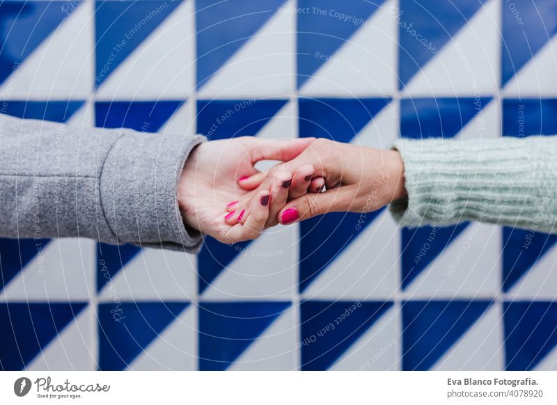 close up of two women holding hands against blue and white tiles. friendship or lgtbi concept lesbian love Porto right person symbol adult homosexual romantic