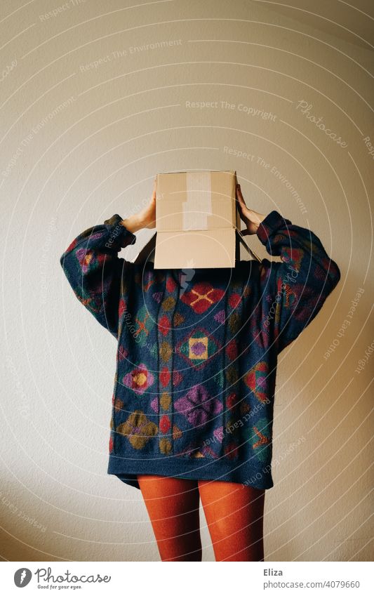 Woman in colorful clothes with a cardboard box on her head Cardboard Crate mail Order Anonymous Hide Exasperated Package variegated Carton Packaging Sweater