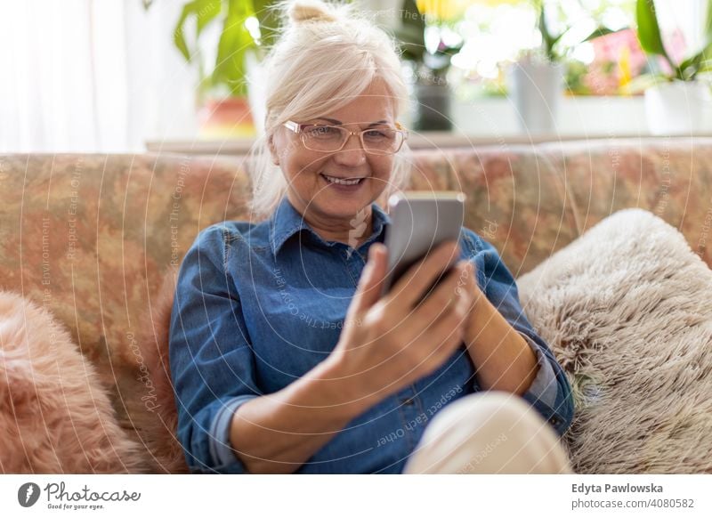 Senior woman using mobile phone at home smiling happy enjoying positivity vitality confidence people senior mature casual female Caucasian elderly house old