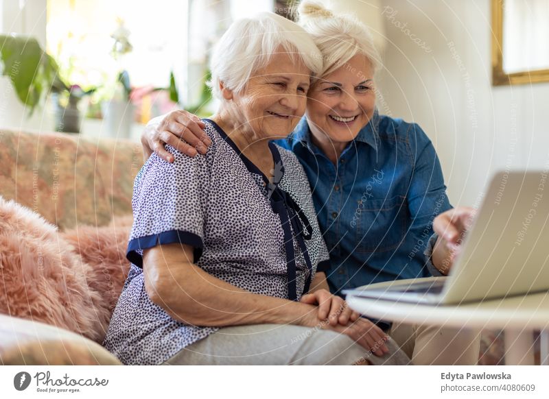 Mature daughter teaches her older mother to use the laptop Computer two persons Bonding Family Mother Daughter Love Together Visit Parents Friends kind Support