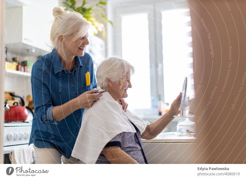 Woman cutting her elderly mother's hair at home smiling happy people woman senior mature female house old domestic life grandmother pensioner grandparent