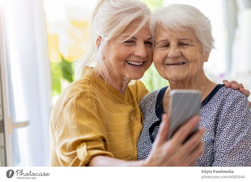Senior woman and her adult daughter using smartphone together smiling happy enjoying positivity vitality confidence people senior mature casual female Caucasian