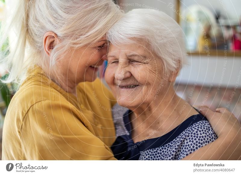 Woman hugging her elderly mother smiling happy enjoying positivity vitality confidence people woman senior mature casual female Caucasian home house old aging