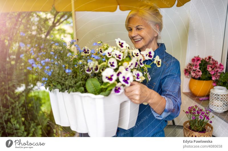 Senior woman taking care of her plants on the balcony smiling happy enjoying positivity vitality confidence people senior mature casual female Caucasian elderly