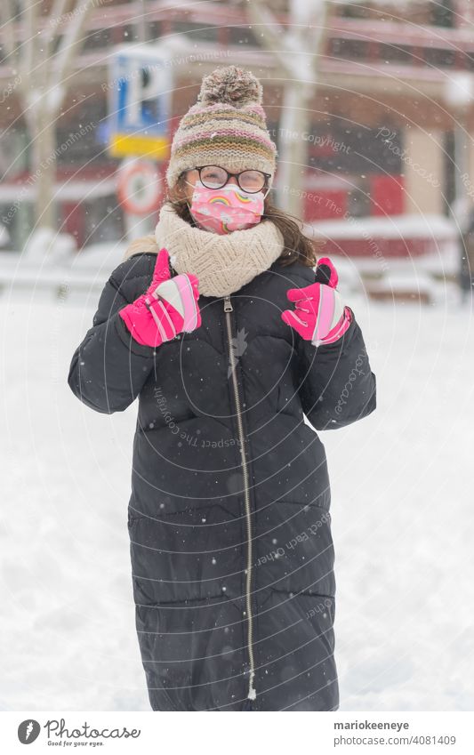 Portrait of a caucasian little girl with a coronavirus mask and her glasses fogged up due to a snowfall innocence responsibility illness loneliness gesturing