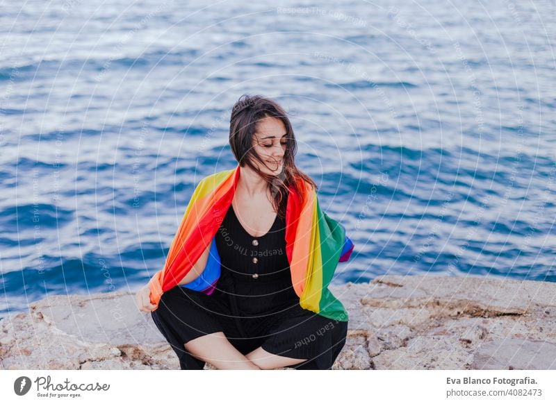 young beautiful woman holding a rainbow gay flag outdoors. LIFESTYLE an pride concept. love is love day community proud sex life festival couple freedom june