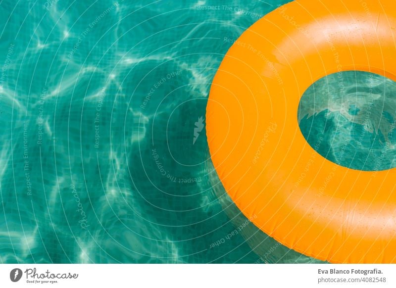 orange inflatable donut on blue water in a swimming pool. Summer fun summer party summertime beautiful float female leisure relax background ring sunny holiday