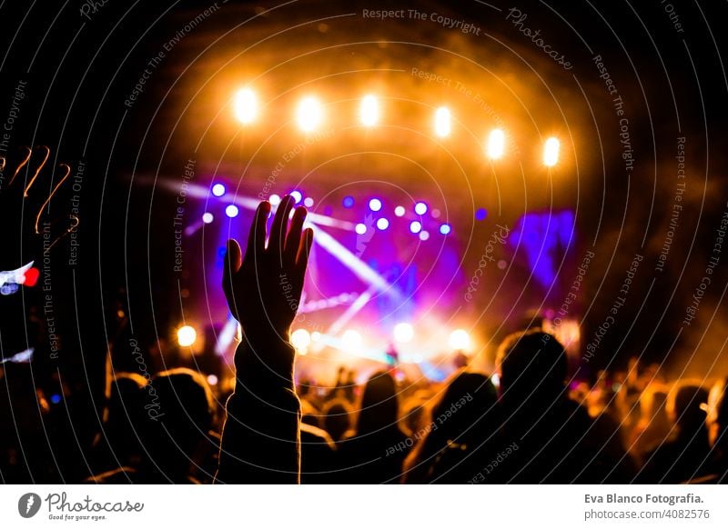 Picture of a lot of people enjoying night perfomance, large unrecognizable crowd dancing with raised up hands and mobile phones on concert. nightlife fan live