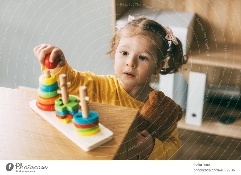 A little girl sorts colorful geometric shapes. Development of motor skills. Development of motor skills and styling of figures. development education desk child