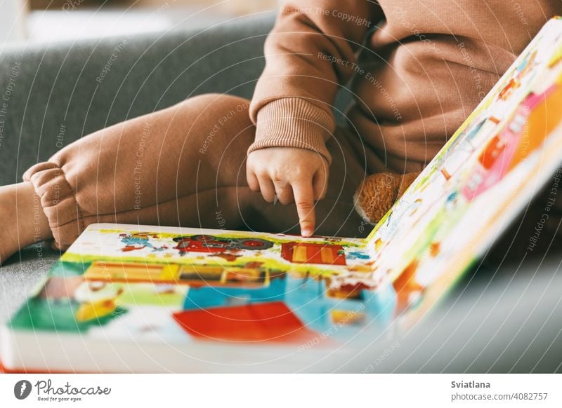 Close-up of a children's educational book with colored pictures in the hands of a little girl. Development, education, childhood sitting toddler happiness home