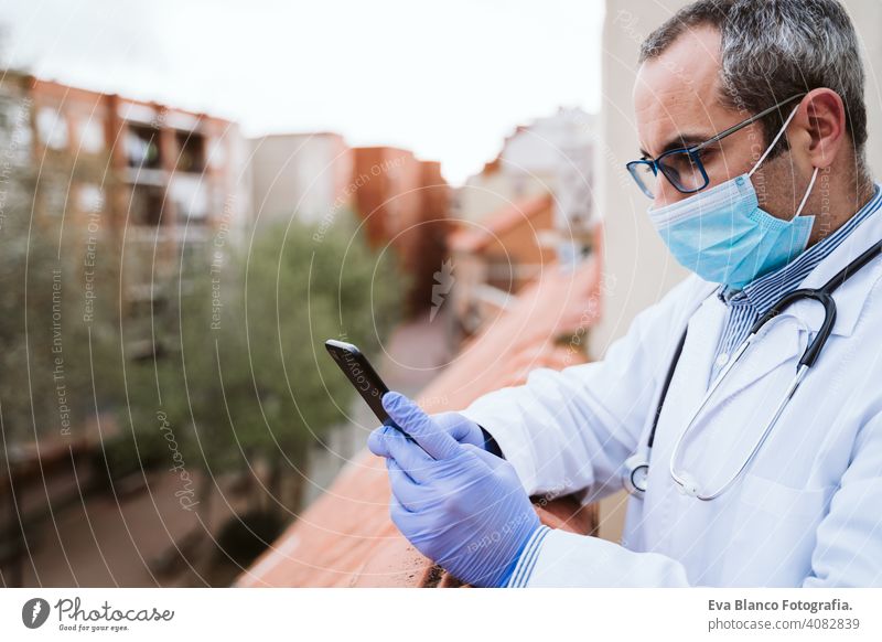 doctor man taking a break, using mobile phone. Wearing protective gloves, mask and stethoscope. coronavirus covid-19 concept corna virus protective mask