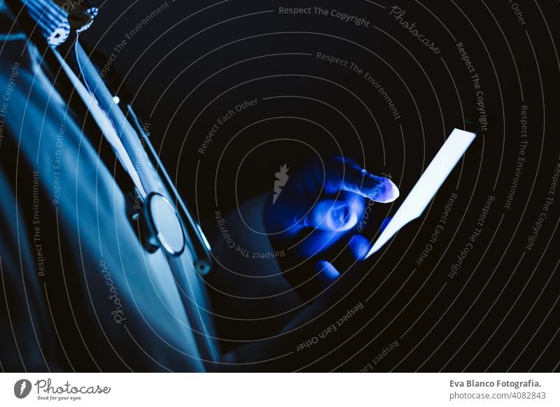 doctor man indoors, using mobile phone. Wearing protective gloves, mask and stethoscope. coronavirus covid-19 concept internet tecgnology dark corna virus