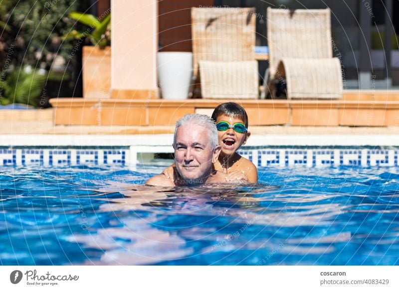 Grandpa and grandson playing on a swimming pool at summer active activity adult baby boy caucasian cheerful child childhood elderly enjoy enjoyment family
