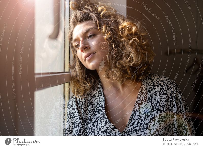 Young woman looking out of window lockdown stay at home covid coronavirus pandemic quarantine social distancing illness epidemic infection safety covid-19