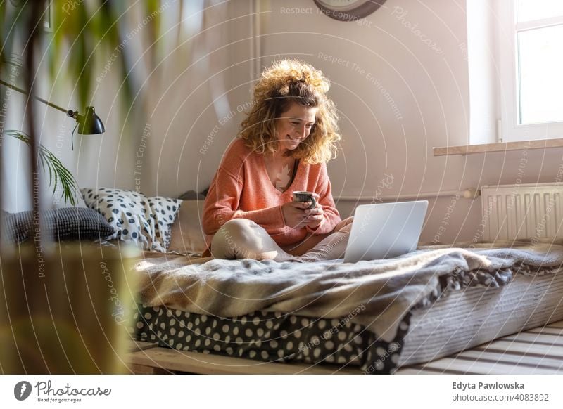 Young woman working in bed at home with laptop education learning studying homework book e-learning technology computer internet online communication wireless