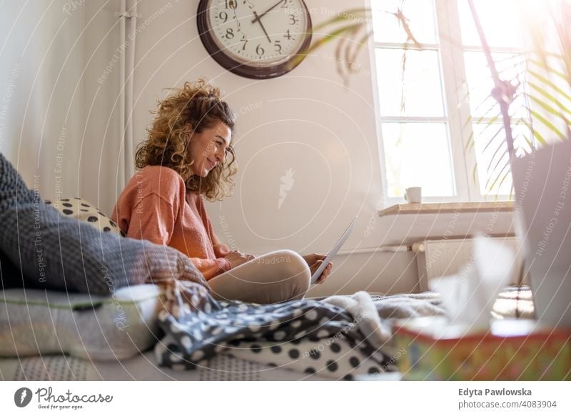 Young woman working in bed at home with laptop education learning studying homework book e-learning technology computer internet online communication wireless