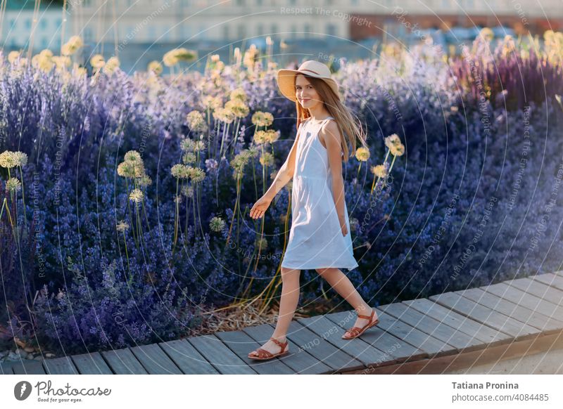 Smiling little girl in white dress and hat walk in lavender city park childhood violet summer sun cute kid toddler smile happy fun play lifestyle people purple