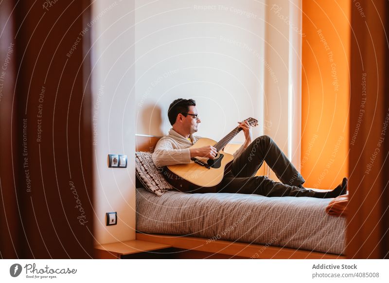 Man playing the guitar on the bed man music sitting home bedroom person male instrument musician young people caucasian using house rock indoors apartment