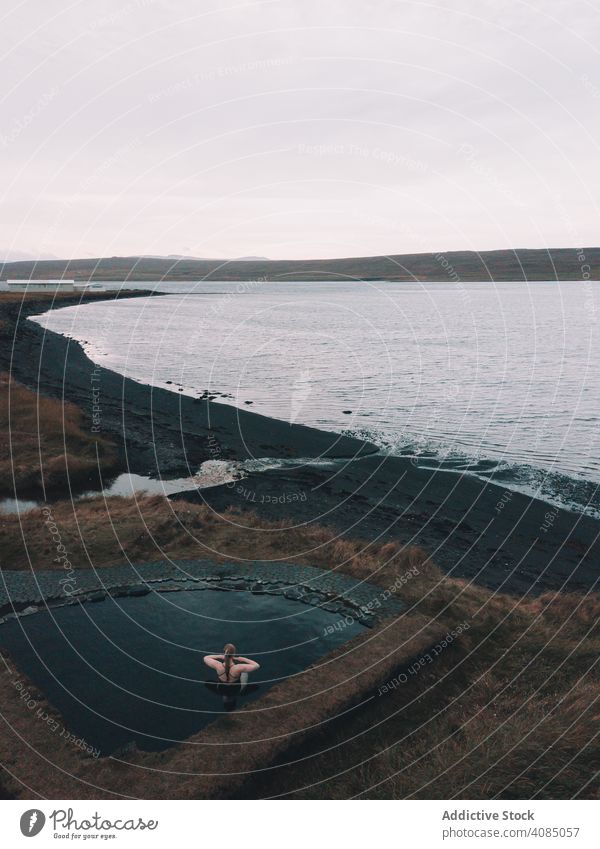 Woman sitting in pool near shore of sea woman young resting water seacoast grass sky cloudy dry female ocean relaxation healthy nature leisure lifestyle heaven