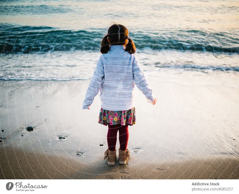 back view of little girl looking at sea - a Royalty Free Stock