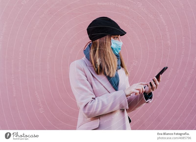 caucasian woman in the street wearing protective mask and using mobile phone. corona virus concept outdoors technology internet public adult infection space