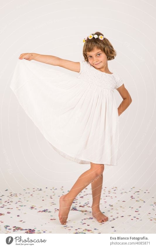 indoor portrait of a kid having fun. confetti on the floor. white dress on little girl portrait. indoors, confetti on the floor. white  background child cute