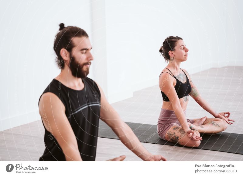 Fit young couple doing acro-yoga at sea beach. Man lying on concrete plates  and balancing woman on his feet. Beautiful pair practicing yoga together. -  a Royalty Free Stock Photo from Photocase