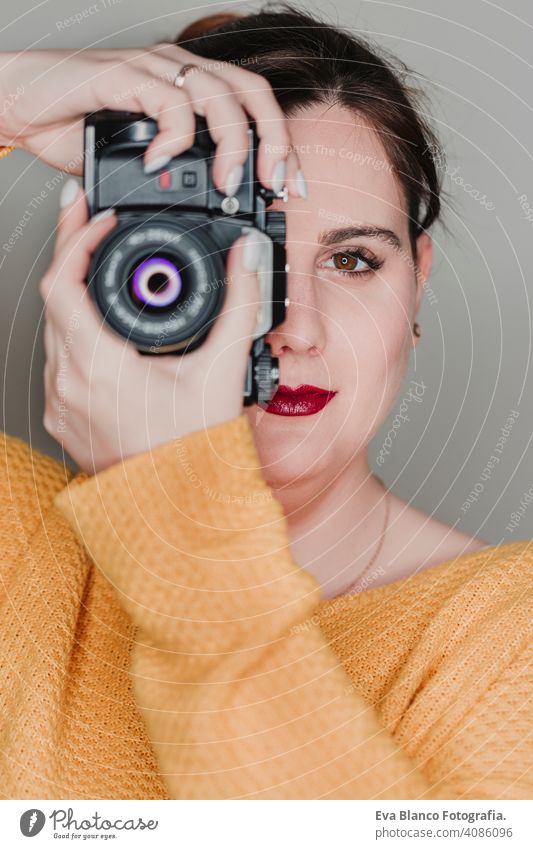 close up portrait of a young woman holding a camera. Photography concept casual attractive happy photographer paparazzi professional photography lens modern art
