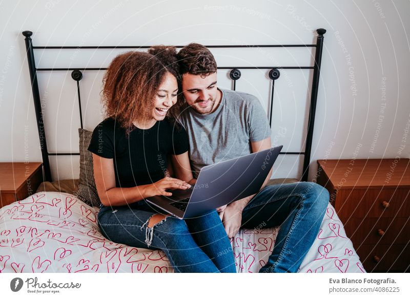 happy couple in love at home. Afro american woman and caucasian man using laptop. ethnic love concept technology afro american bed indoors valentine mixed race