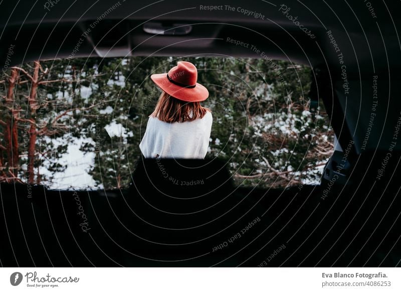 portrait outdoors at the mountain of young woman wearing winter clothes. back view snow forest hat blanket modern relax nature enjoy green cold hipster car