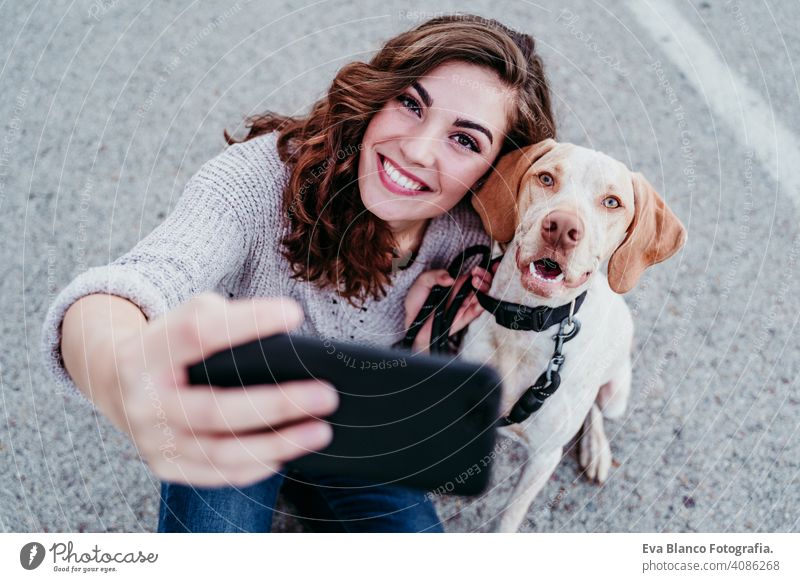 young woman taking a selfie with mobile phone with her dog at the street. autumn season picture photo technology park outdoors love pet owner sunny beautiful