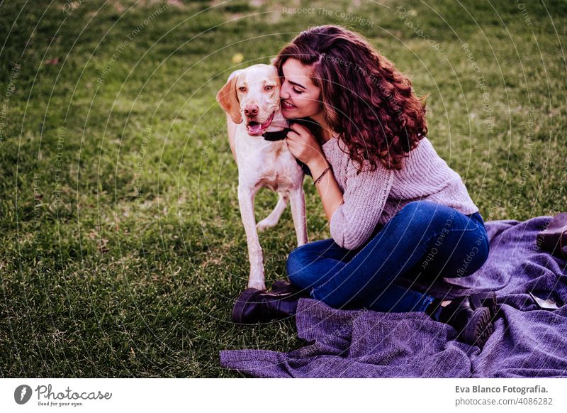 young woman with her dog at the park. she is hugging the dog. autumn season portrait outdoors love pet owner sunny beautiful happy smile mixed race purebred