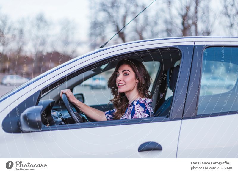 Young woman driving a car in the city. Portrait of a beautiful woman in a car, looking out of the window and smiling. Travel and vacations concepts interior