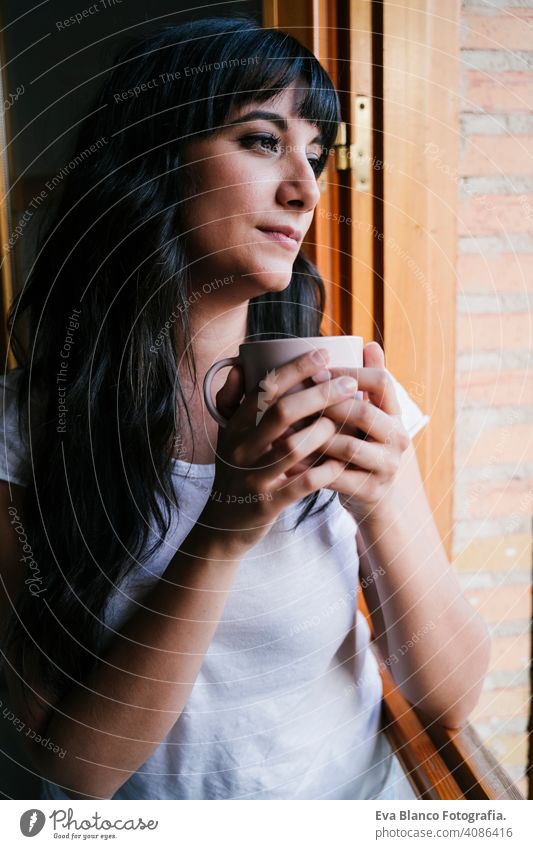 young caucasian woman at home by the window having a cup of coffee or tea. Morning and relax concept. Lifestyle indoors girl comfortable house hotel mug modern