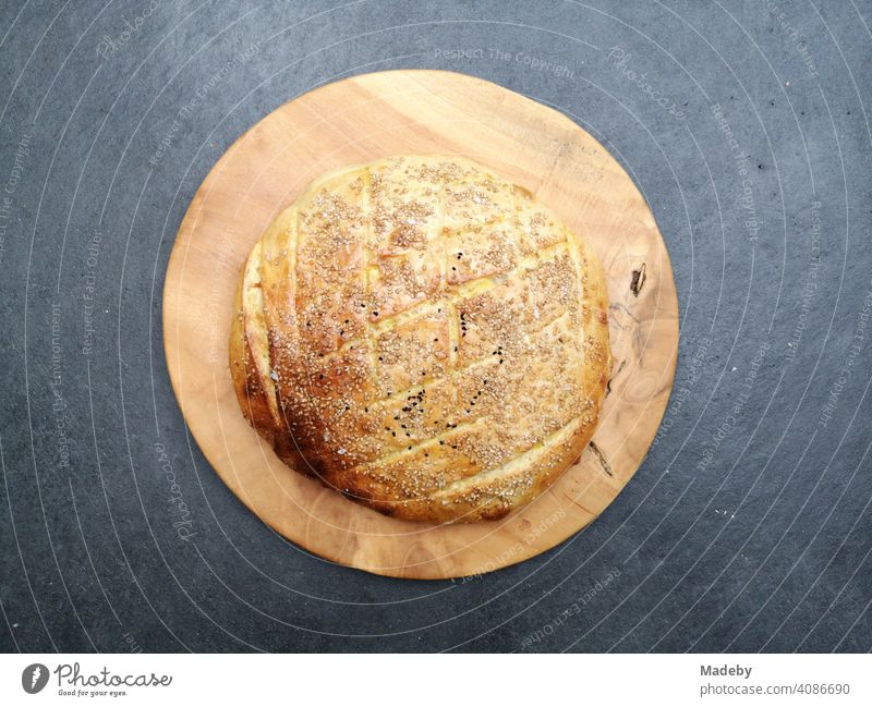 Delicious homemade flatbread on a round wooden plate on a grey concrete floor in the designer apartment of an old farmhouse in Rudersau near Rottenbuch in the district of Weilheim-Schongau in Upper Bavaria