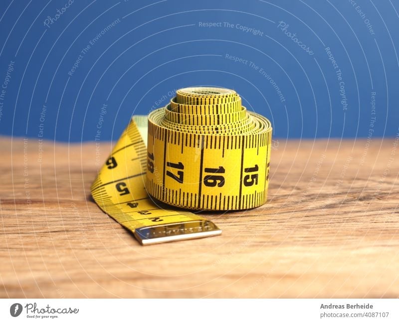 On The Table Is A Yellow Sewing Meter Seamstress Meter For Measuring The  Length And Volume Of The Model The Measuring Tape Lies On A Wooden Board  Stock Photo - Download Image