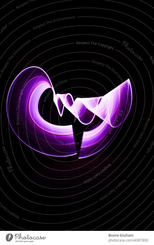 Curved abstract shape made with a light saber violet. Lightpainting session at night. Leds light effect. lightpainting art bright color colorful concept