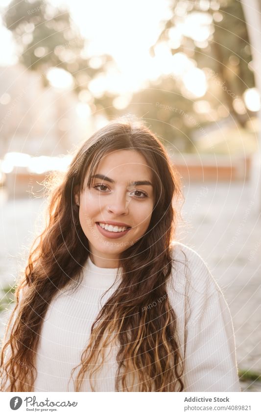 Cheerful young woman in street portrait park city border leaning smiling sunny daytime carefree lifestyle leisure female casual cheerful happy joy fence summer