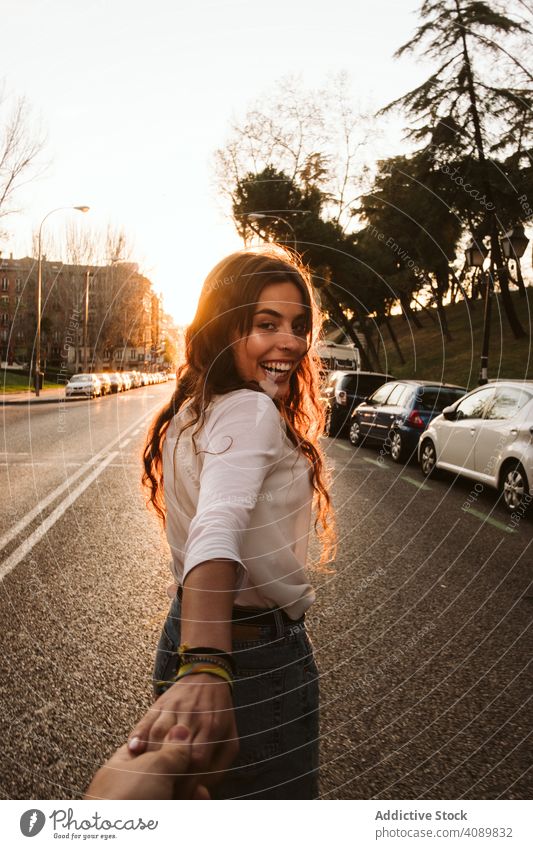 Cheerful woman leading way on city street follow me smiling holding hand road sunset evening young female travel trip tourism sundown dusk twilight town