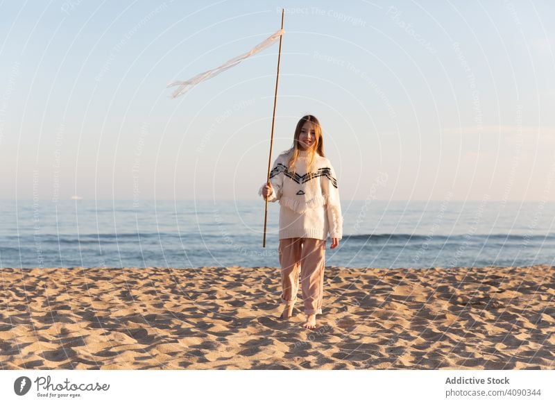 Teen girl with stick and ribbons on beach teen smiling looking away lifestyle leisure nature long hair teenager fun sky cloudless rest relax cheerful harmony
