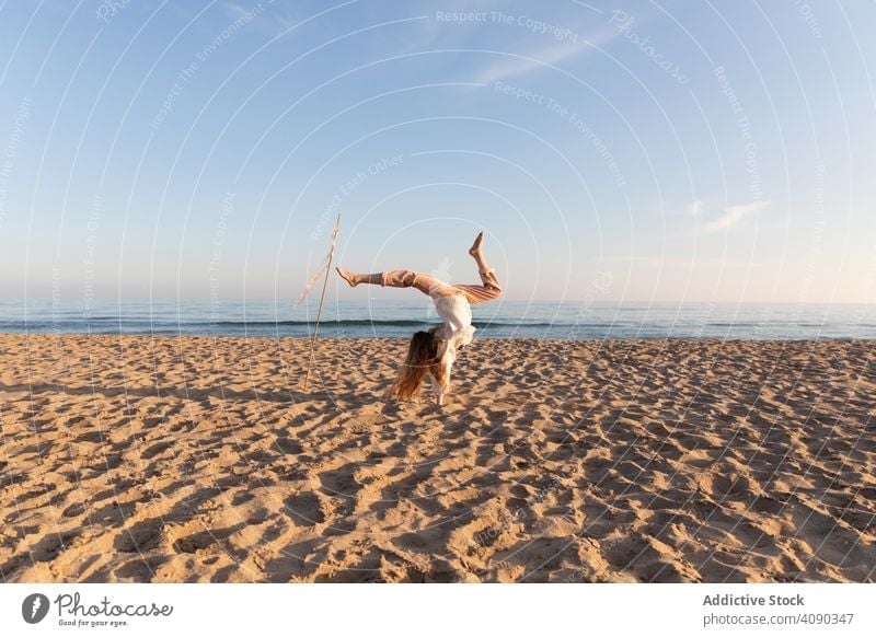 Teen girl with stick and ribbons on beach doing handstand teen smiling looking away lifestyle leisure nature long hair teenager fun sky cloudless rest relax