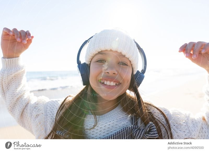 Girl listening to music near sea girl beach smartphone using smiling waves headphones hat casual kid child teen earphones relax rest lifestyle leisure shore