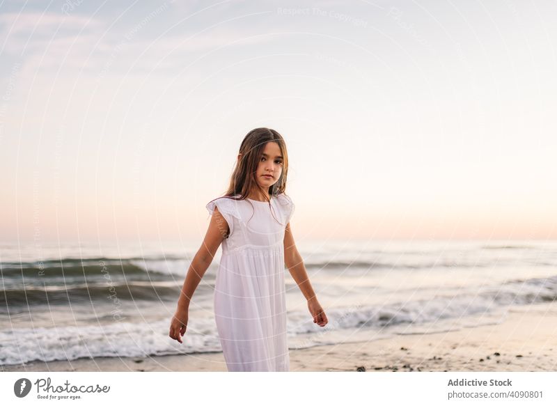 Adorable girl walking and looking at camera on seaside at sunset adorable seashore sunshine beach summer water sunny child childhood happy happiness vacation
