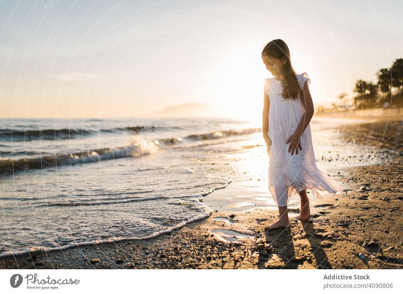 Adorable girl walking and playing on seaside at sunset adorable seashore sunshine beach summer water sunny child childhood happy happiness vacation travel